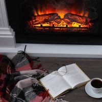 Cozy indoor scene with a fireplace, book, coffee cup, and blanket.