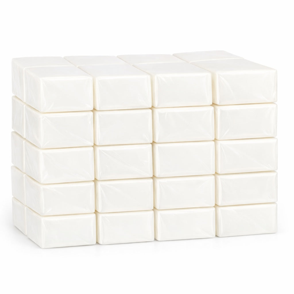 Forty white melt and pour soap blocks individually wrapped stacked in a neat grid on a clean white background. Each black is smooth, rectangular, and wrapped in clear plastic with a soft matte finish, showing a uniform creamy-white color and subtle shadows beneath the stack