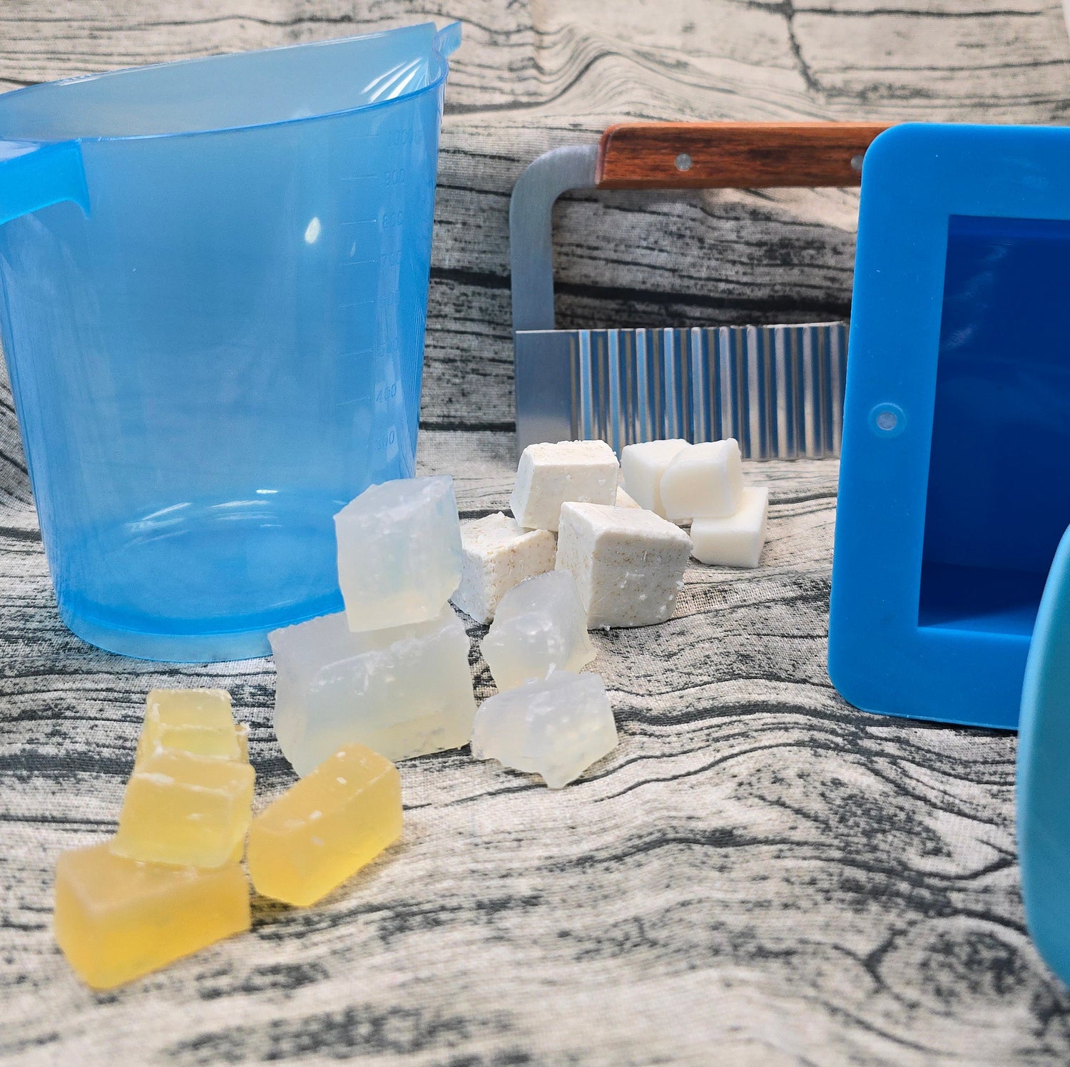 Pieces of SFIC Melt and Pour Soap Base next to Mix and Pour pitcher and soap cutter