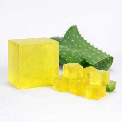 Yellow melt and pour soap bars and cubes with aloe vera leaves on a white background