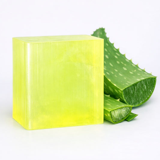 Block of yellow green melt and pour soap base with aloe vera leaves on a white background