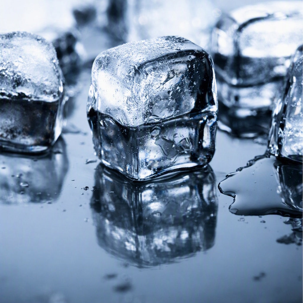 Black Ice Fragrance Oil depiction. A close-up of clear ice cubes on a glossy wet surface with reflections, tinted in a cool blue cast.