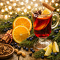 Christmas Splendor Fragrance Oil is represented by a hot toddy drink, cinnamon sticks, juniper berries and orange slices with a pine bough.
