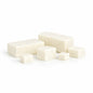 Six creamy white cocoa‑butter melt and pour soap blocks arranged simply on a white surface. Two larger rectangular pieces sit behind four smaller cubes, all with smooth matte texture and soft shadows under even lighting. Each piece could be used as a sample.