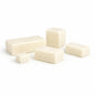 Five creamy white soap base blocks in assorted sizes arranged on a white surface, shown as a goat milk sample.