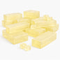 A collection of translucent honey melt and pour soap blocks arranged on a white background. The blocks vary in size, including larger rectangular bars and smaller cubes, all with a warm golden-yellow color and smooth, glossy surfaces. The pieces are grouped loosely together, showing their clarity.