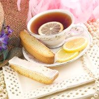 Iced lemon biscotti cookies on a white plate, with a pink floral background