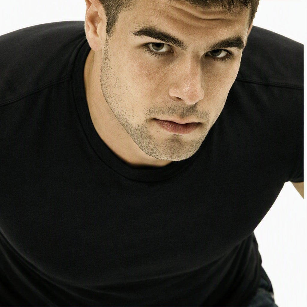 A close-up shot of a man wearing a black crew-neck t-shirt, looking directly at the camera against a plain white background. Used to represent the Issey Miyake Fragrance Oil.