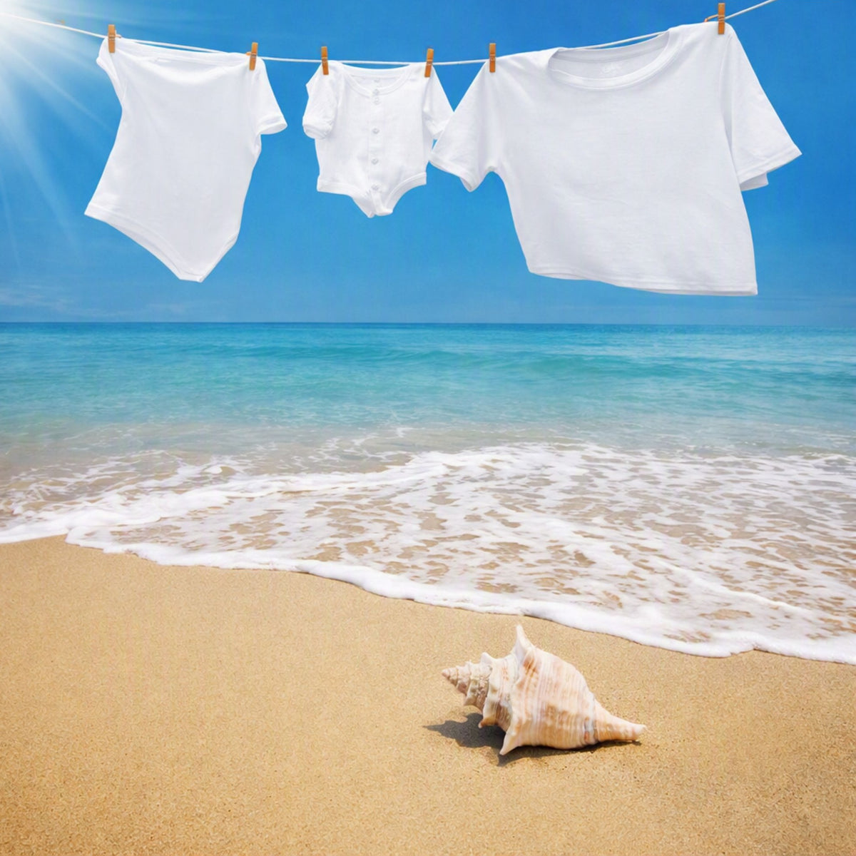 Three white linen clothing piece hang on a string line with wooden clothespins against a sunny beach backdrop with turquoise ocean water, white waves, and a sandy shore with a seashell in the foreground. To give the feel for Ocean Shore Linen Fragrance Oil.