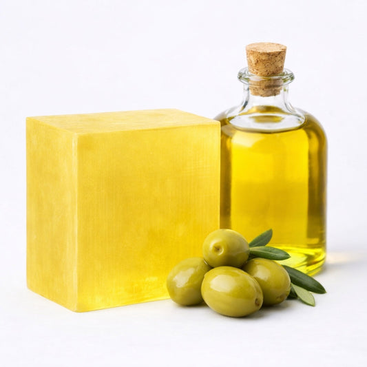 Olive Melt and Pour Soap Base for handmade soap — translucent golden‑yellow block next to olive oil and green olives on a white background.