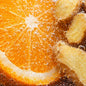 A close-up of a bright orange slice with ginger root pieces bubbling in a carbonated liquid, showing detailed citrus segments, bubbles, and warm golden ginger tones. To depict the smell of Orange Ginger Fizz fragrance oil.