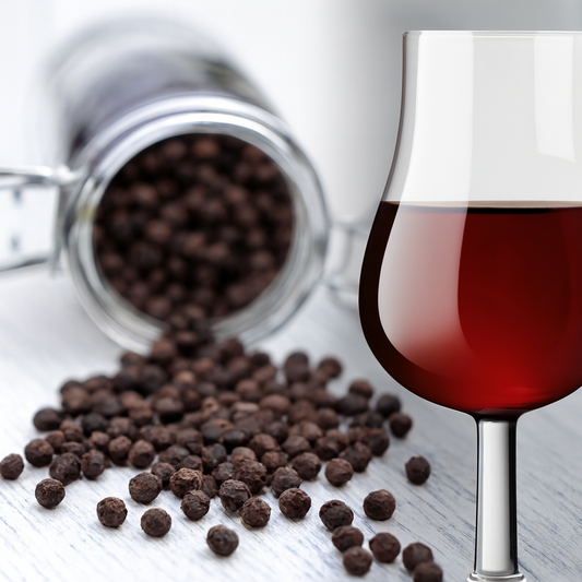 Visual for Pepper and Port Fragrance Oil — black peppercorns spilling from glass jar beside red port wine glass on white-gray table.
