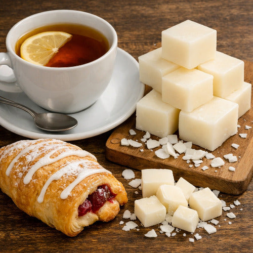 Tea with lemon, pastry, and soap base chunks on a wooden surface