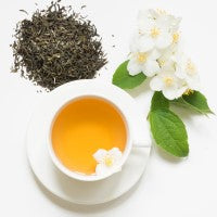 Tea cup with green tea leaves, jasmine flowers fragrance oil, and leaves on a white background