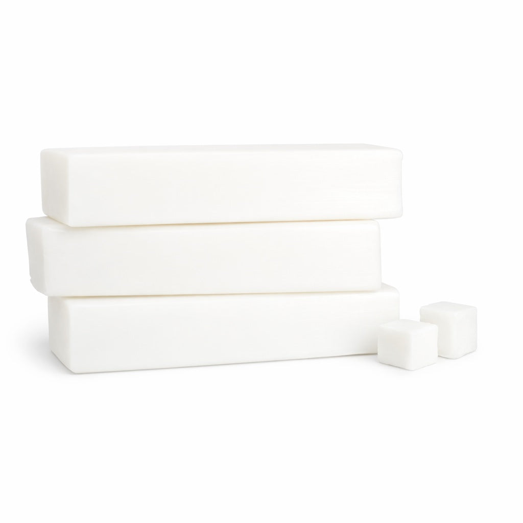 Three white soap bars stacked on a white background with two white cubes of cut up soap base